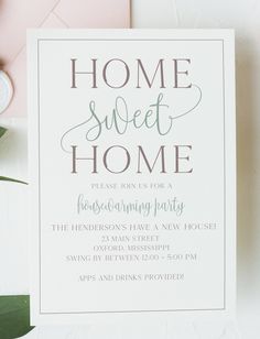 a white card with the words home sweet home on it next to a plant and envelope