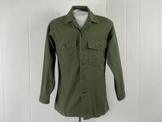 "Vintage 1970s Viet Nam era US Army military shirt, O G shirt. Made of green cotton sateen. Has two chest pockets and button down front. About a size medium.  Actual measurements are:  44\" at the chest,  40\" at the waist.  18\" shoulder seam to shoulder seam: 22\" shoulder seam to cuff  29\" overall length  In very good condition." Green Military Style Button-up Shirt, Military Style Collared Shirt For Fall, Fall Military Collared Shirt, Khaki Military Collared Shirt, Khaki Collared Military Shirt, Olive Military Style Button-up Top, Olive Military Style Collared Top, Military Style Cotton Shirt For Fall, Military Style Collared Cotton Top