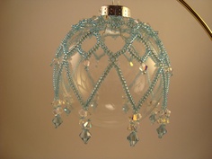 a glass ornament hanging from a light fixture with beads and crystals on it