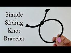 a hand holding a black string with the words simple sliding knot not bracelet on it