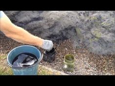 a person is holding a bucket with something in it and there are rocks behind them