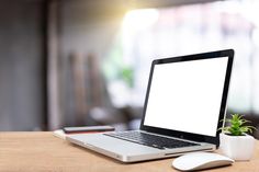 an open laptop computer sitting on top of a wooden desk next to a mouse and plant