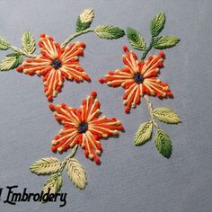 three embroidered flowers with green leaves on a blue background and the word embroidery written in white