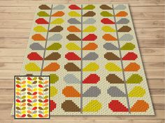 a colorful rug with leaves on it next to a wooden floor and a piece of fabric