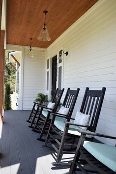 a row of rocking chairs sitting on top of a wooden porch