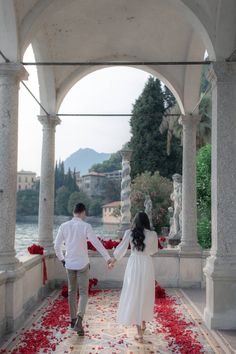 a man and woman holding hands while walking through an archway