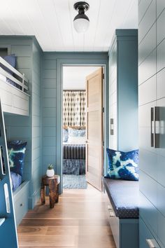 a room with bunk beds and blue walls, wood flooring and wooden stairs leading up to the bedroom