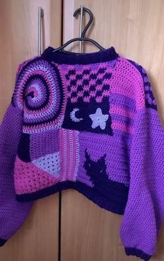 a purple sweater hanging on a wooden door