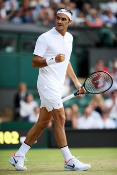 a man holding a tennis racquet on top of a tennis court with people in the background