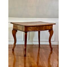 a wooden table sitting on top of a hard wood floor next to a white wall