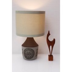 a table lamp next to a small wooden horse figure on a white surface with a beige shade