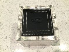 a black and white square shaped object with stitching on the edges, sitting on a marble surface