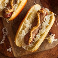 two hot dogs with toppings on a cutting board