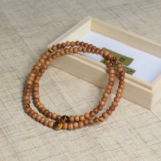 6mm Sandalwood Beads Bracelet Characteristics of the product Material : sandalwood, Silk elastic cordLength : about 16cmMain beads : sandalwood about 5mm (※Main beads size & color are a little different dipending on lots)Head bead : tiger eye about 8mm Handmade in Kyoto, JAPAN About Sandalwood Sandalwood is the second-most expensive wood in the world, it has a distinctive soft, warm, smooth, creamy, and milky precious-wood scent that has been high valued for centuries.Sandalwood is mentioned in Traditional Brown Beads For Meditation, Brown Hand-strung Beaded Bracelets For Meditation, Spiritual Brown Carved Beads, Sandalwood Bracelet, Bohemian Hand-strung Jade Bracelets, Popular Scents, Sandalwood Scent, Kumihimo Bracelets, Buddhist Traditions