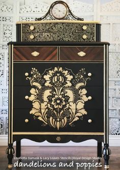 a black and gold dresser with ornate designs on the front, along with a clock