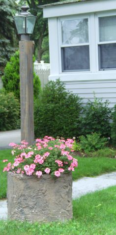 a lamp post with pink flowers in front of a house