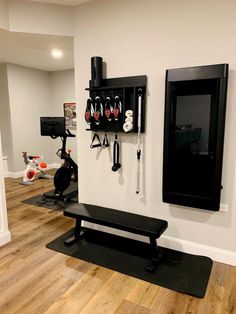 a home gym with black and white accessories hanging on the wall next to an exercise bench