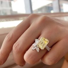 a woman's hand holding a yellow and white diamond ring