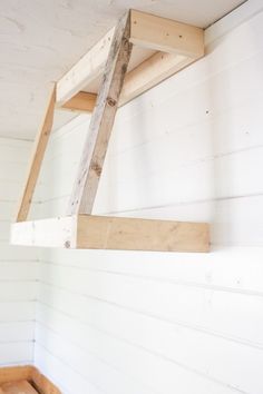 a wooden ladder is hanging from the ceiling in a room with white walls and wood paneling