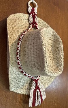 a straw hat hanging on a wooden door with red and white string around it's brim