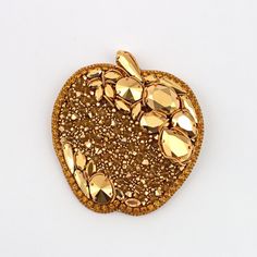 an apple shaped brooch with gold sequins