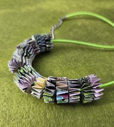 a necklace made out of folded books on a green surface with a string attached to it