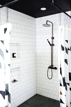 a bathroom with black and white tiles on the floor, shower head, and curtain