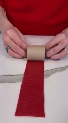 a person is using a roll of toilet paper to make a red ribbon on a white surface