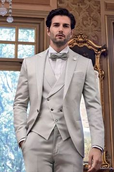 a man wearing a suit and bow tie standing in front of a mirror with his hands in his pockets