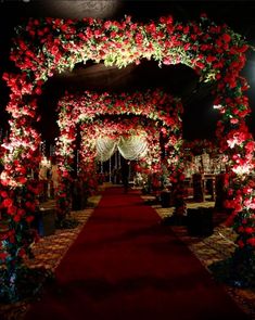 a red carpeted aisle decorated with flowers and greenery