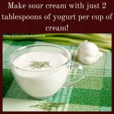 a cup of yogurt next to garlic on a green tablecloth with the words make sour cream with just 2 tablespoos of yogurt per cup of cream