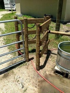 a wooden gate is next to a metal barrel