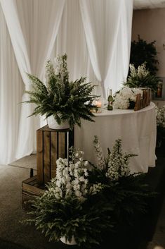 a table with flowers and candles on it in front of white draping curtains