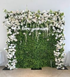 an artificial flower wall with white flowers and greenery