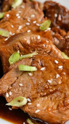 some meat with sauce and green onions on a white plate