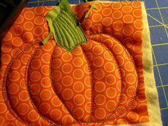 an orange pumpkin quilted on top of a cutting board