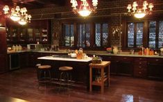 a large kitchen with lots of counter space and lights hanging from the ceiling above it