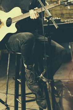 a man sitting in front of a microphone while holding a guitar and singing into a microphone