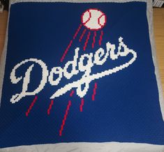 a crocheted blanket with the word dodgers on it and a baseball flying through the air