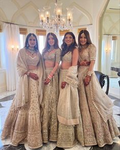 three women in matching outfits posing for the camera with chandelier and chandelier