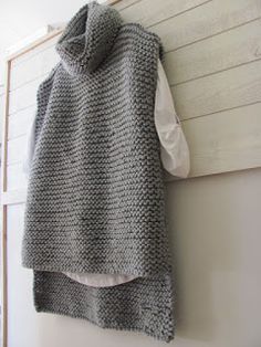 a knitted sweater hanging on the wall next to a door with an open hood