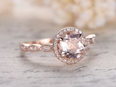 an engagement ring with a pink morganite surrounded by white diamonds on a marble surface