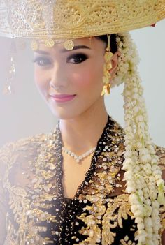 a woman wearing a gold and black outfit with flowers in her hair is smiling at the camera