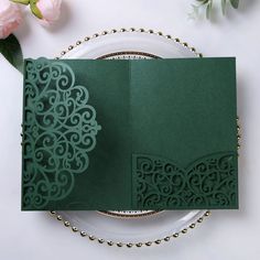 a green wedding card on a plate next to flowers