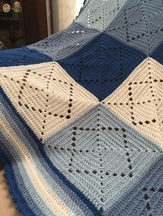 a blue and white crocheted blanket sitting on top of a bed