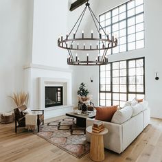 a living room filled with furniture and a chandelier hanging over the fire place