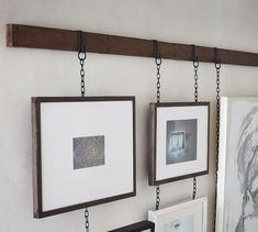 two framed pictures hanging on a wall next to a couple of frames with chains around them