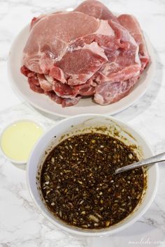 two bowls filled with meat sitting on top of a white marble counter next to an empty bowl