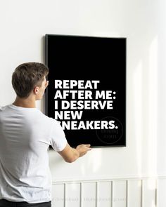 a man holding up a black poster with white lettering that reads repeat after me i deserve new breakers