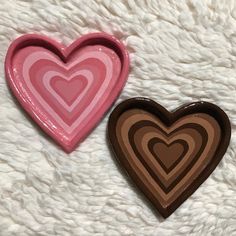 two heart shaped trays sitting on top of a white blanket